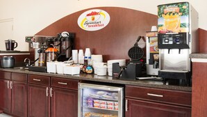 A breakfast station with coffee machines, a juice dispenser, and a cooler with packaged food.