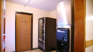 A hallway with a private door, a vending machine, and a refrigerator.