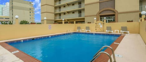 A rectangular swimming pool with a tiled edge, surrounded by a brick border.