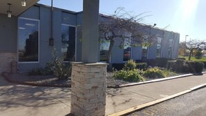 A modern building with a stone pillar, large windows, and a clear sky. - Motel6 Oriskany, NY (Oriskany)