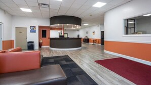 A lobby with a reception desk, seating area, and a large window. - Motel6 Oriskany, NY (Oriskany)