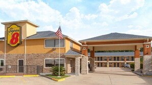 Un hôtel de la chaîne Super 8, avec un mât portant un drapeau, un parking et une entrée.