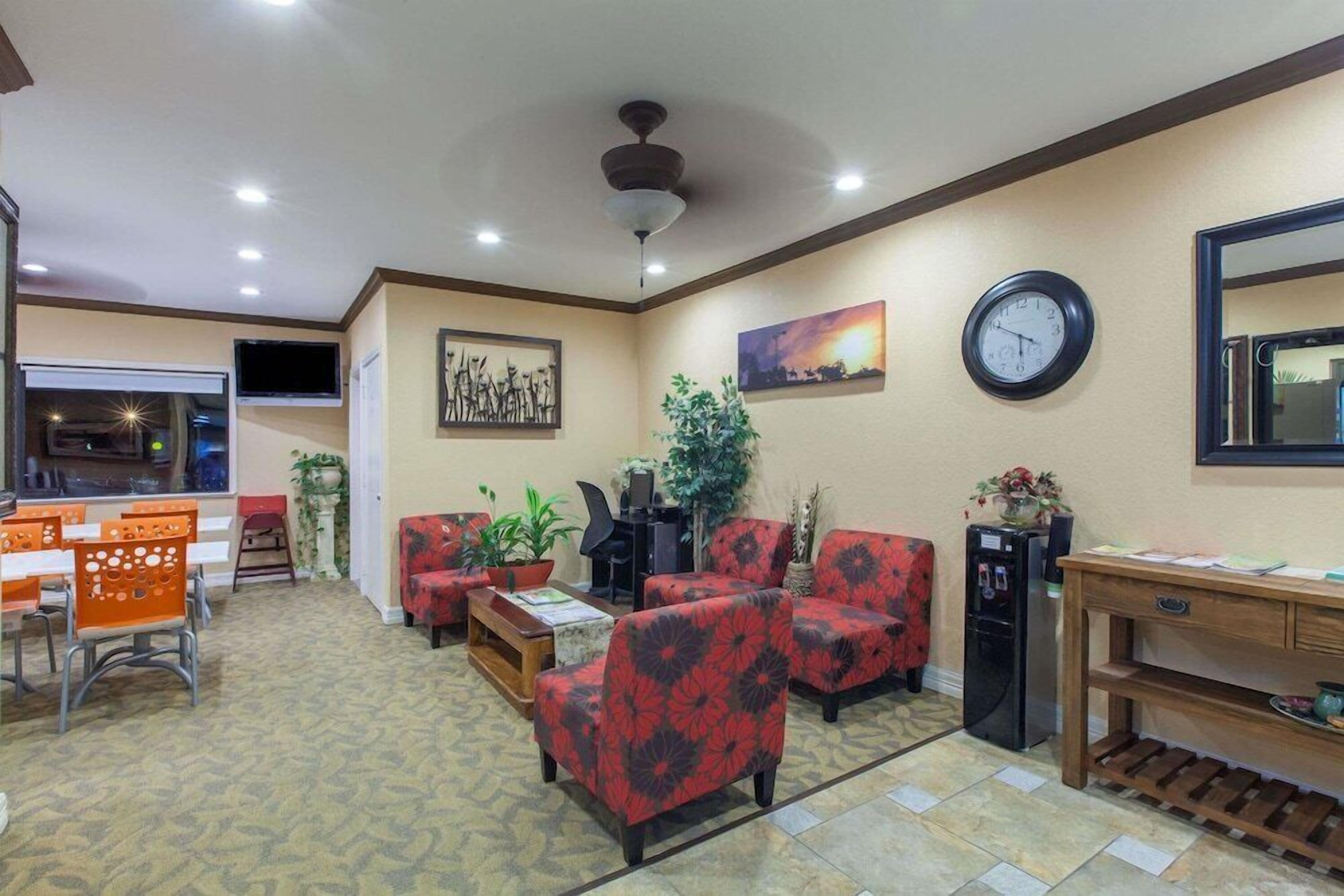 A hotel lobby with a dining area, seating, a clock, and a ceiling fan.