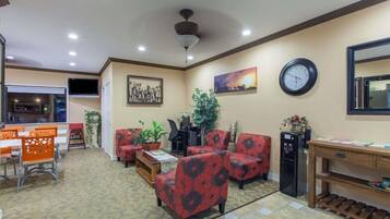 A hotel lobby with a dining area, seating, a clock, and a ceiling fan.