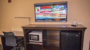 Une chambre d’hôtel équipée d’un téléviseur fixé au mur, qui affiche une liste des chaînes, d’un bureau avec un micro-ondes et d’un réfrigérateur.