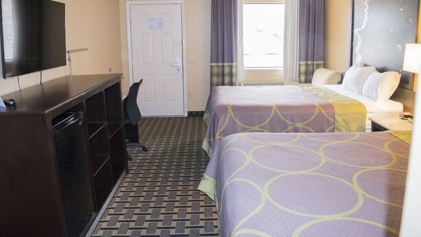Une chambre d’hôtel avec un lit, un bureau, une télévision et une porte.