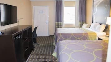 A hotel room with a bed, a desk, a TV, and a door.