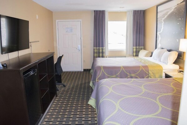 A hotel room with a bed, a desk, a TV, and a door.