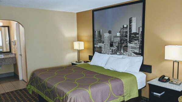 A hotel room with a bed, a nightstand, a lamp, a phone, and a cityscape view.