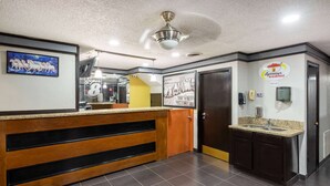 A hotel reception area with a wooden reception desk, a ceiling fan, a clock, and a Super 8 sign. - Super 8 By Wyndham Tulsa/arpt/st Fairgrounds (Tulsa)