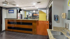 A hotel lobby with a reception desk, a large mirror, a ceiling fan, and a sign indicating a Super 8 hotel. - Super 8 By Wyndham Tulsa/arpt/st Fairgrounds (Tulsa)