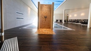 Un interior modern amb una paret de pedra, una banca i una zona de seients amb cadires.