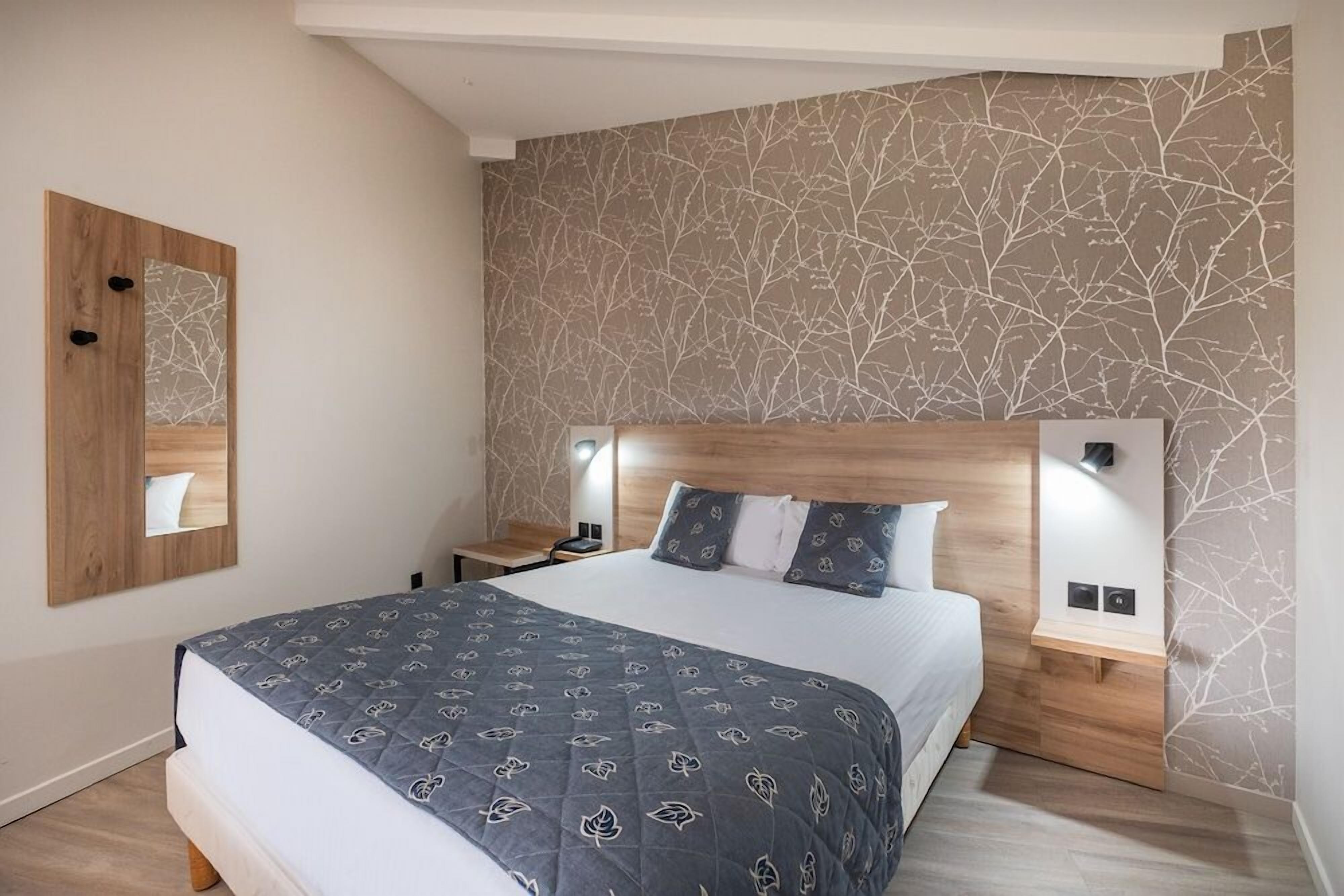 A bedroom with a bed, bedside tables, a nightstand, a mirror, and a wall with a leaf pattern.