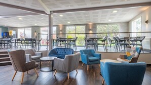 Un espai interior ampli amb mobiliari modern, grans finestres i un balcó.