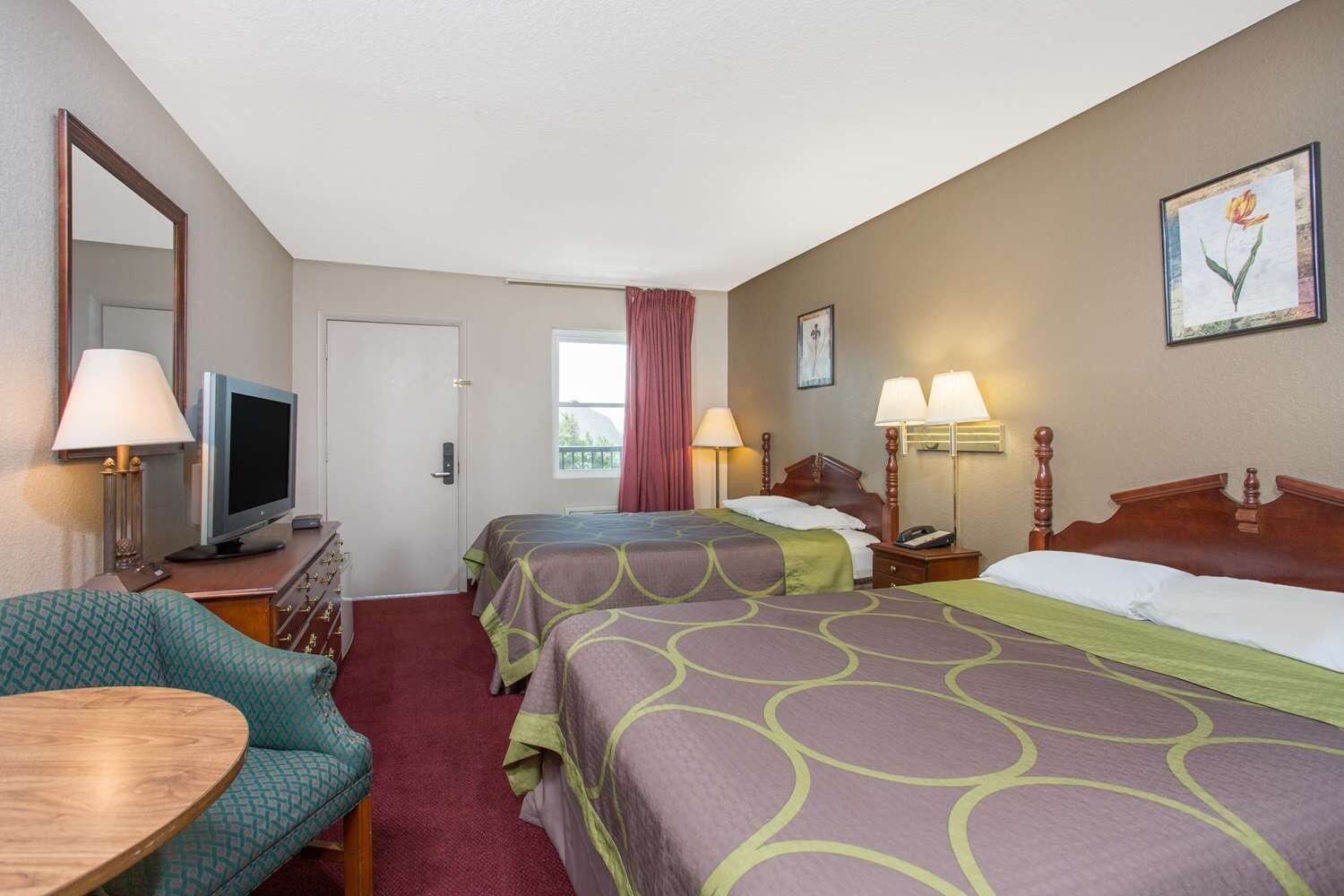 A hotel room with two beds, a TV, a desk, and a chair.