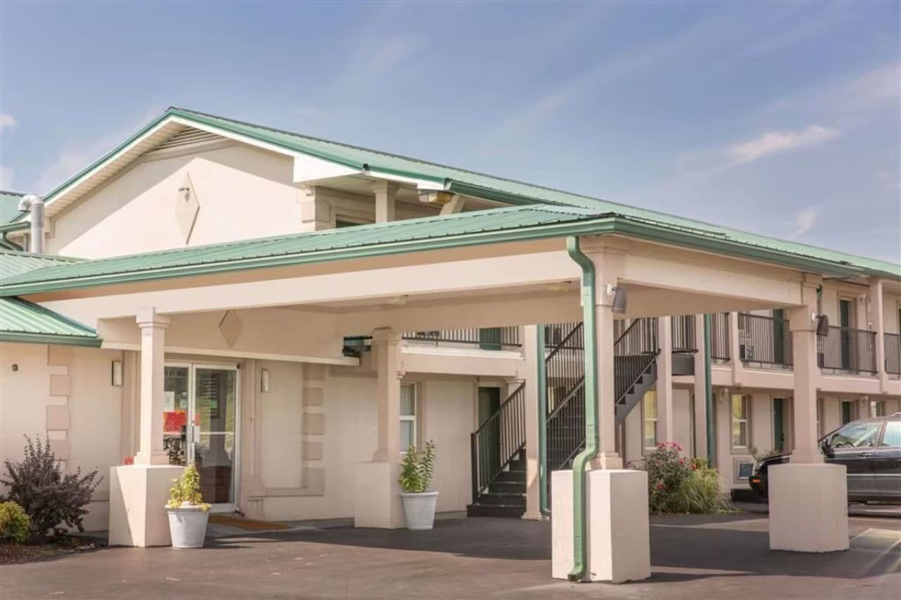 A two-story motel with a covered entrance and a parking area.