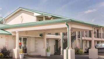 A two-story motel with a covered entrance and a parking area.