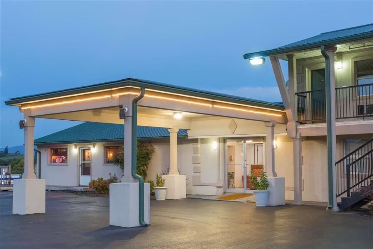 A hotel with a covered outdoor area, a staircase, and a well-lit entrance.