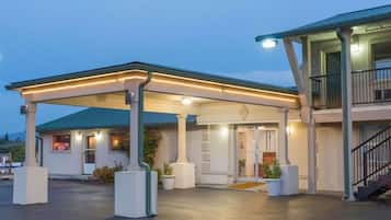 A hotel with a covered outdoor area, a staircase, and a well-lit entrance.