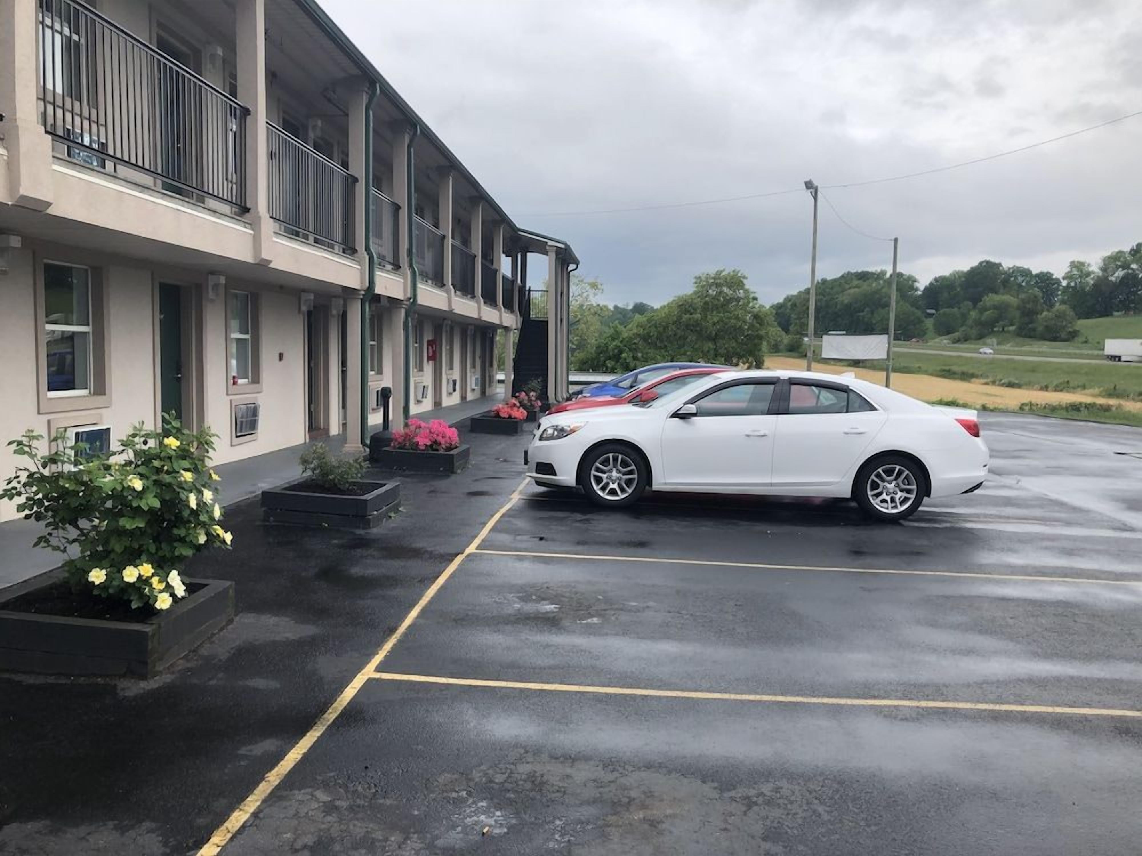 A parking lot with a white car parked in front of a building with multiple windows and balconies.