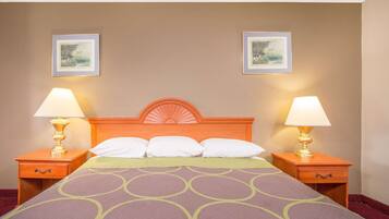 A hotel room with a bed, two nightstands, two lamps, and two framed pictures on the wall.