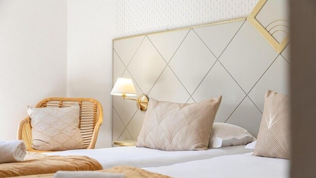 A hotel room with a bed, a chair, a lamp, and a wall with a geometric pattern. - The Originals City, Hotel Bristol, Le Puy-en-velay (Le Puy-en-Velay)