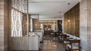 A modern interior with a dining area, seating, and a kitchen in the background. - Aber Unaiza (Unaizah)