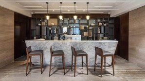 A modern kitchen with a marble island, bar stools, pendant lighting, and built-in shelving with decorative items. - Aber Unaiza (Unaizah)