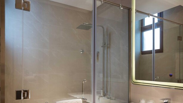 A modern bathroom with a glass-enclosed shower, a vanity with a mirror, and wooden cabinets. - Aber Unaiza (Unaizah)