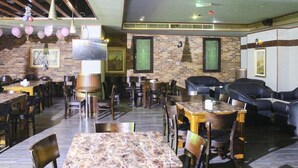Un restaurante con paredes de ladrillo, mesas de madera y sofás de cuero negro.