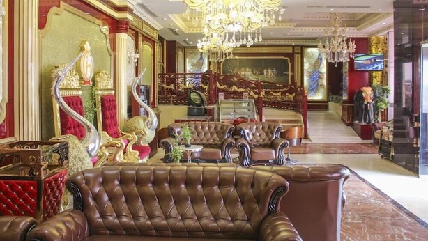 Un lobby lujoso con una gran araña, muebles ornamentados y una escalera.