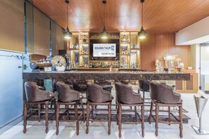 A bar area with a wooden ceiling, a marble countertop, and bar stools. - Golden Tulip Suites Gurgaon by Inde Hotels (Sohna)
