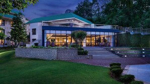 Un edificio moderno con fachada de vidrio, un muro de contención de piedra y un césped bien cuidado.