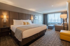 A hotel room with a large bed, a sofa, a desk, and a window with curtains. - Best Western Premier Airport/expo Center Hotel (Louisville)