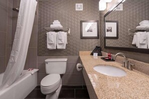 A bathroom with a bathtub, toilet, sink, and towel racks. - Best Western Premier Airport/expo Center Hotel (Louisville)