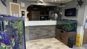 A reception area with a fish tank, a counter, and a caution sign on the floor. - Motel6 Greenville, NC Ecu-medical Center (Greenville)