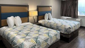 A hotel room with two beds, each with a patterned bedspread, a nightstand with a lamp, and a window with curtains. - Motel6 Greenville, NC Ecu-medical Center (Greenville)