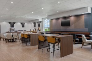 A modern restaurant with a bar area, multiple seating options, and a large TV screen. - Galveston INN Suites Hotel (Galveston)