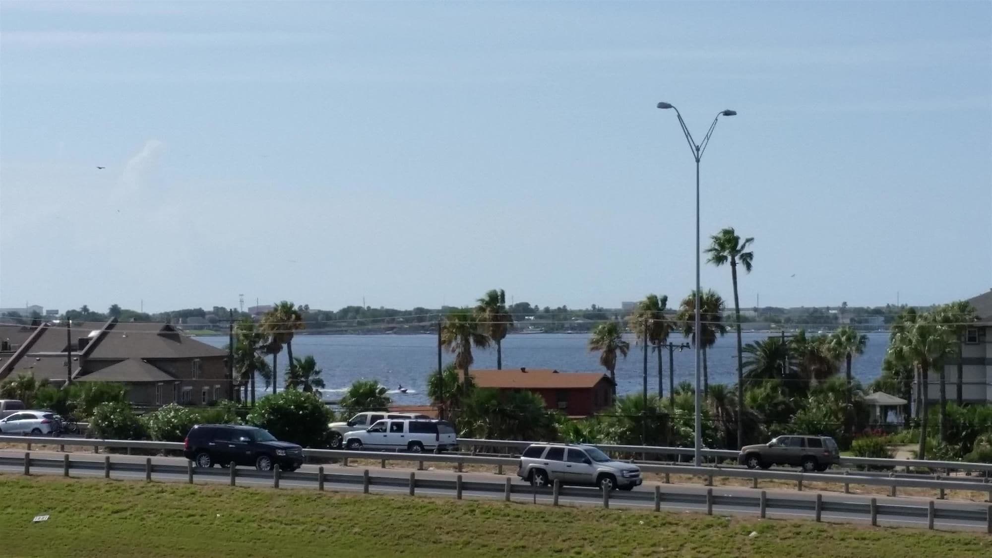 Una carretera costera con vehículos, un puente y una masa de agua.