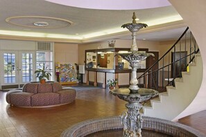 A spacious lobby with a central fountain, a reception desk, and a staircase. - Days Inn by Wyndham Gainesville University (Gainesville)