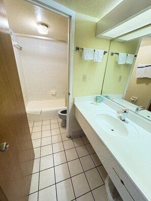 A bathroom with a sink, mirror, and shower. - Days Inn by Wyndham Gainesville University (Gainesville)