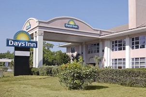 Um hotel Days Inn com um posto de gasolina, área de estacionamento coberta e um edifício com várias janelas.