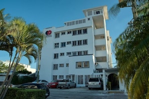 Un edificio a più piani con facciata bianca, diverse finestre e un logo rosso sul lato.