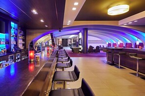 A bar area with seating, a counter, and shelves with bottles.
