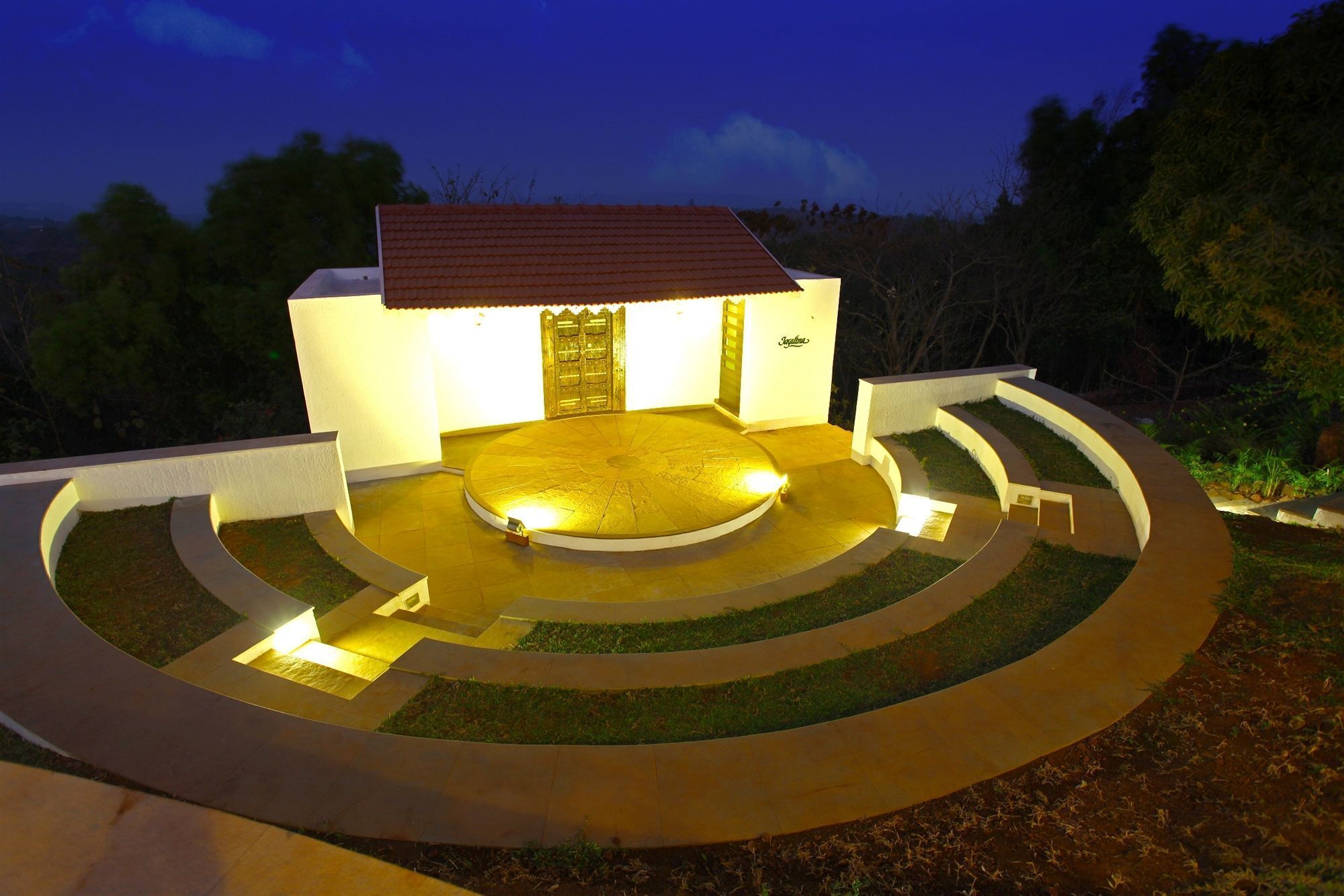 A modern building with a circular driveway, a gated entrance, and a well-lit exterior.