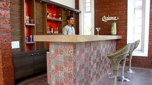 A bar area with a patterned tile wall, shelves with bottles and glasses, and a sign reading 'Quiana'.