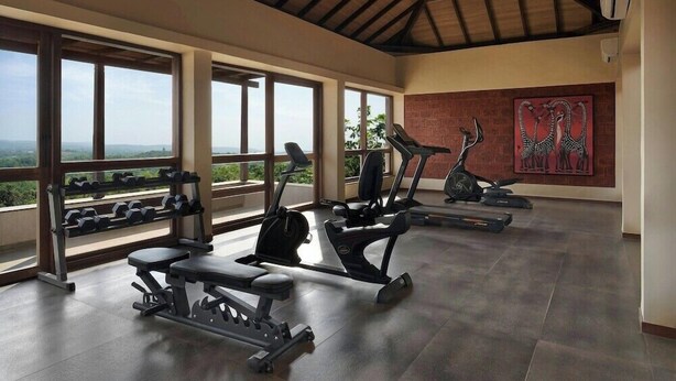 A gym with exercise equipment, large windows, and a view.