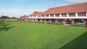 A building with a red roof, white walls, and a large green lawn.