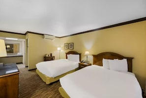 Une chambre d’hôtel avec deux lits, un bureau, une lampe et une table de chevet.