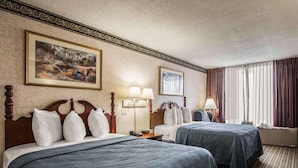 Una habitación de hotel con dos camas, un cuadro en la pared y un ventanal con cortinas.